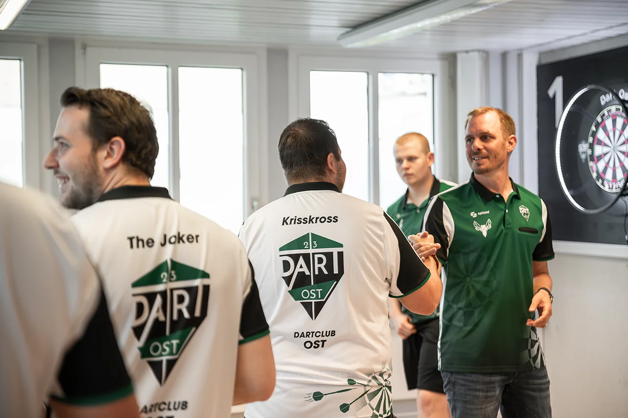 Spieler in Dart-Ost-Trikots begrüssen sich im Vereinslokal